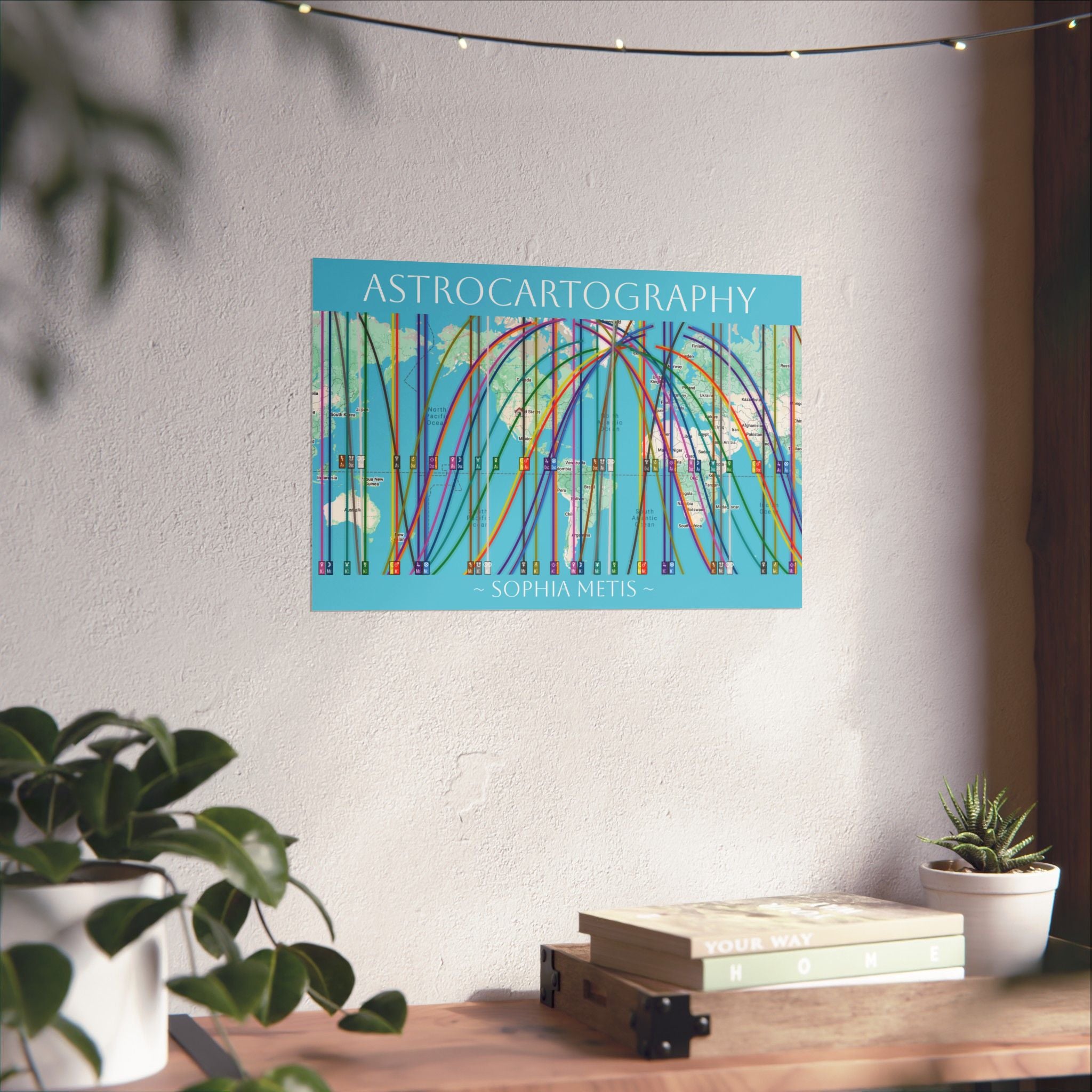 Colorful 'Astrocartography' poster on a wall above a desk with plants and books.