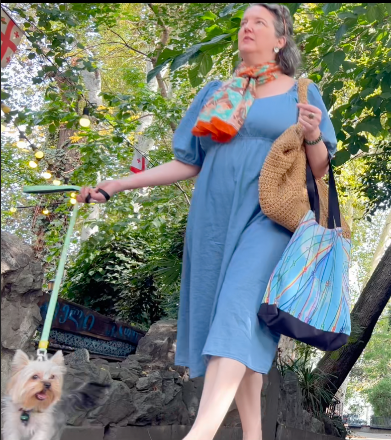 woman walking a dog through the city while carrying her personalized astrocartography tote bag and shopping for produce